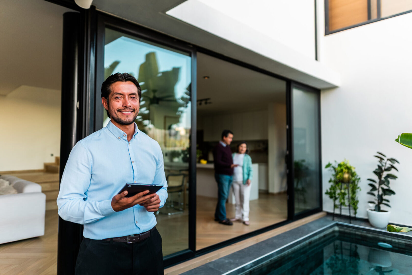 Man smiling by pool with tablet.